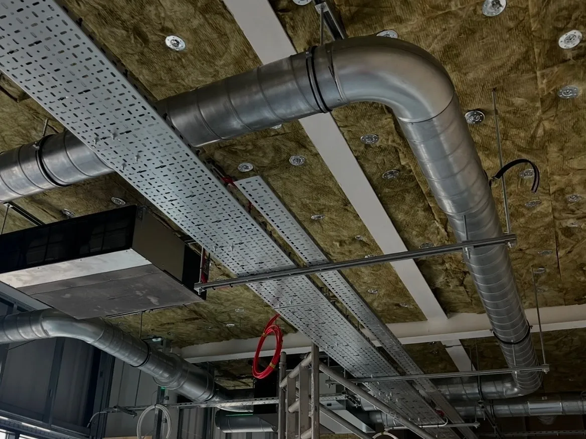 New spiral ductwork and a suspended air-handling unit installed at high level on a commercial site